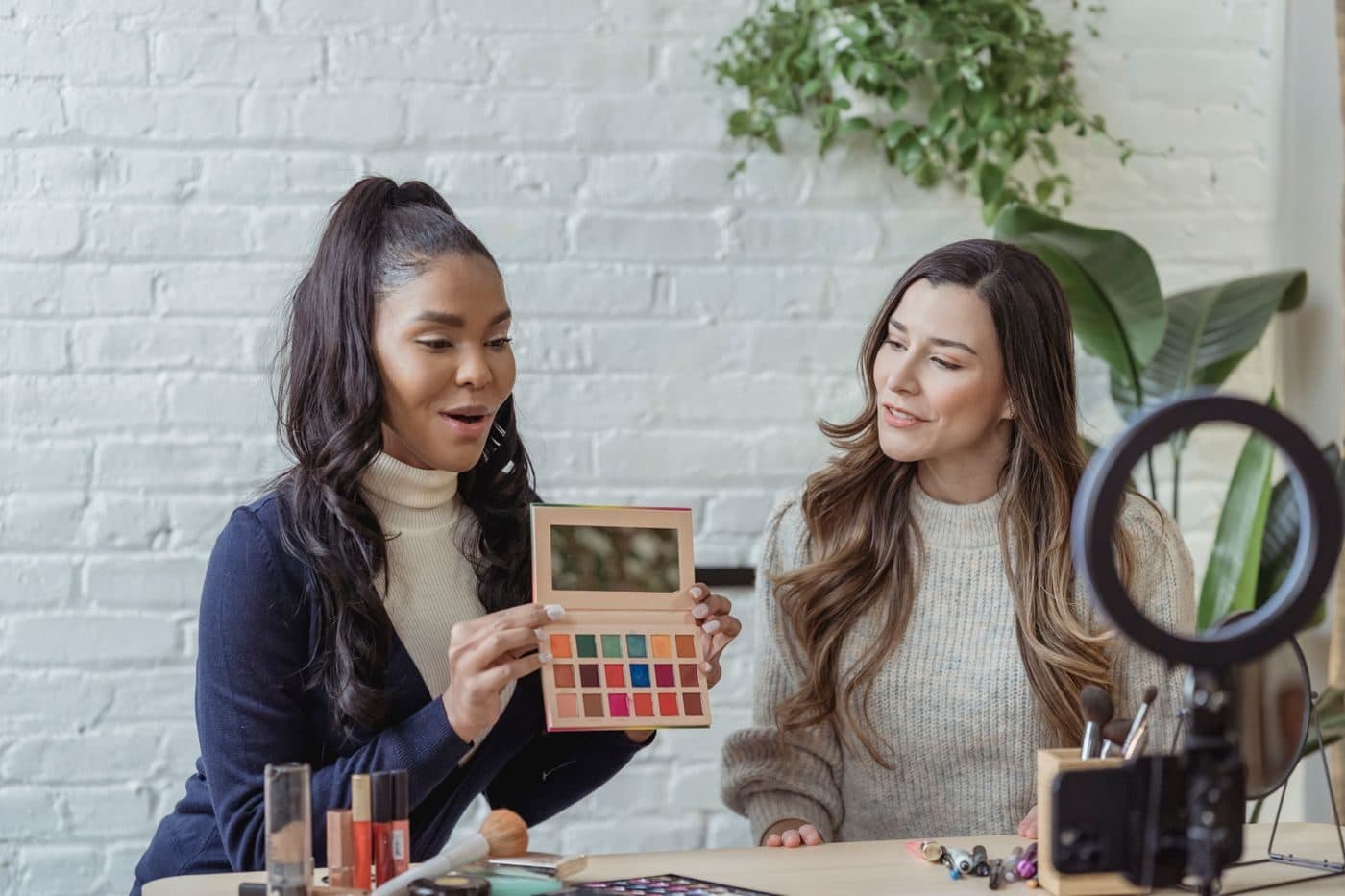 Two creators reviewing an eyeshadow palette to camera